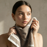Model demonstrating Italic Sorrel Australian Cotton Towels, showing soft, plush washcloth in a bathroom setting