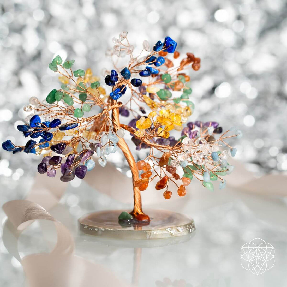 Crystal tree sculpture representing chakra energies, with colorful gemstones on a wooden base, by Conscious Items.
