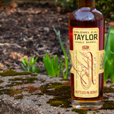 Bottle of Colonel E.H. Taylor Single Barrel Bourbon Whiskey in a clear glass with a black and gold label.