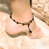 Black obsidian grounding anklet with silver accents from Conscious Items, featuring smooth oval stones and adjustable chain for ankle wear.