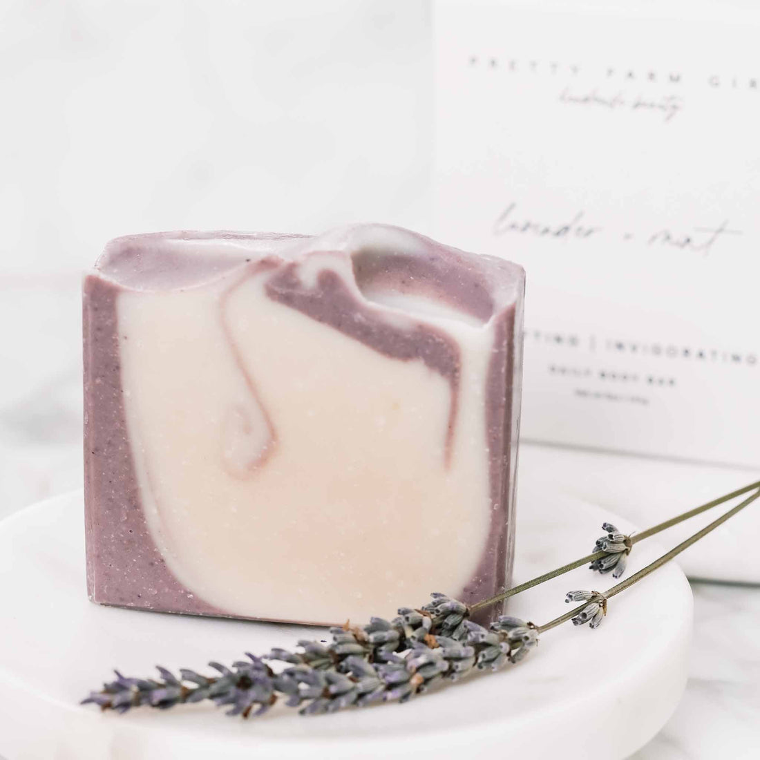 Lavender and mint handmade tallow and goat milk soap bar from Pretty Farm Girl, displayed in a box with floral accents.
