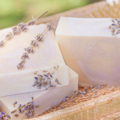 Lavender and mint handmade tallow and goat milk soap bar by Pretty Farm Girl, outdoors with fresh lavender and mint leaves.