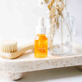 Pretty Farm Girl Rose Glow Anti-Aging Face Serum in a sleek bottle with rose petals around, highlighting natural ingredients.