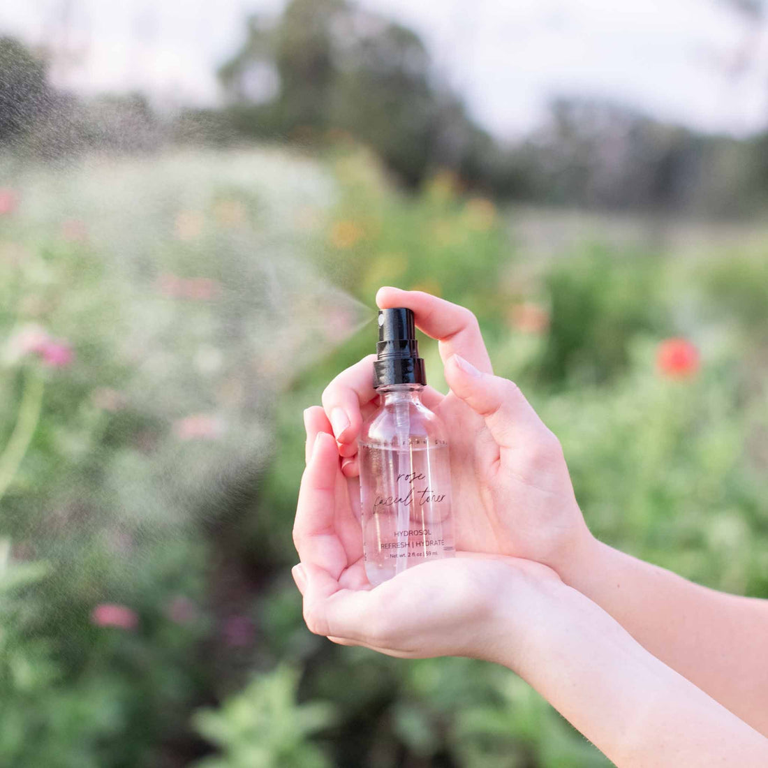 Organic Pure Rose Facial Toner by Pretty Farm Girl, featuring a clear bottle with rose-infused toner and fresh roses in the background.