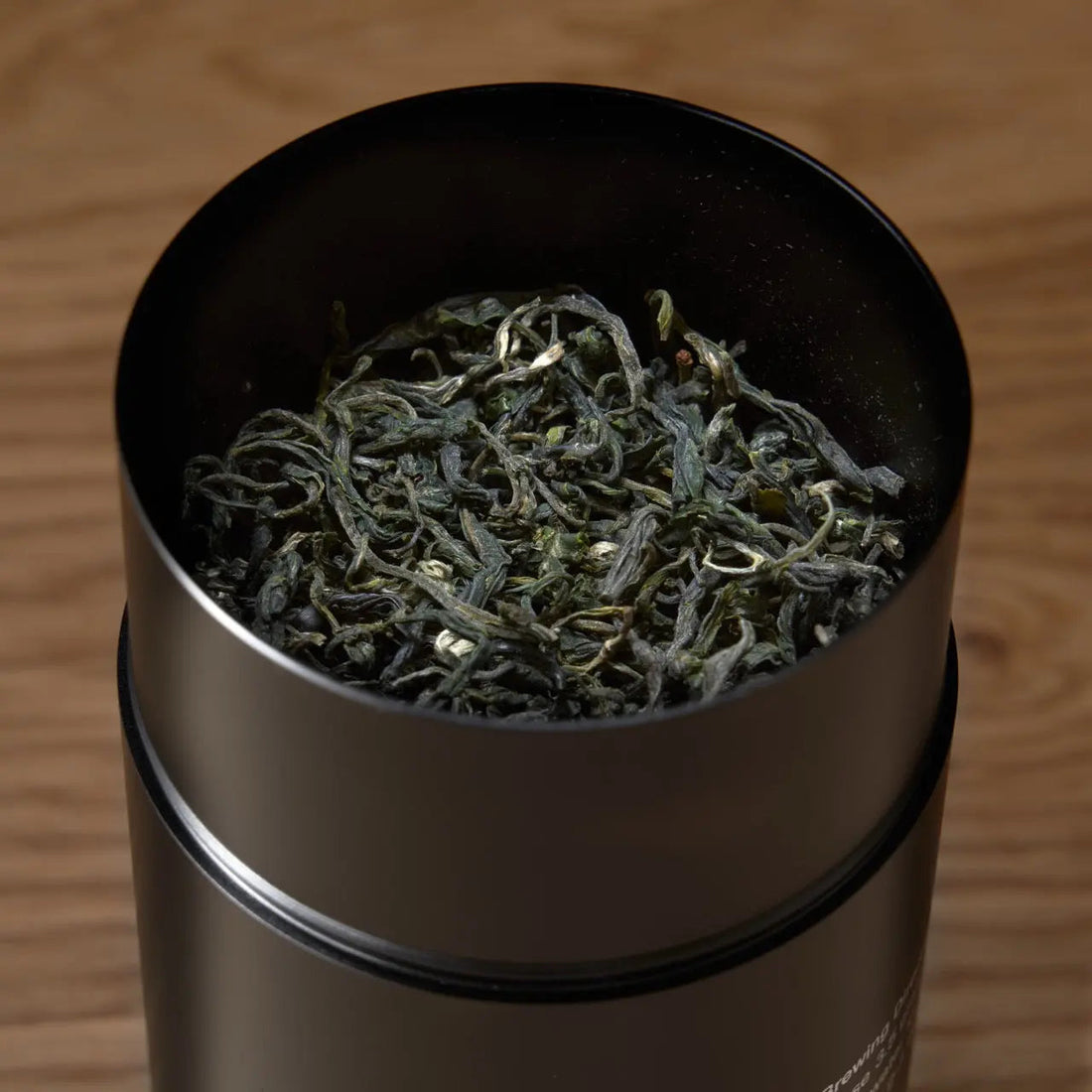 Open tin of All The Rare Leaves luxury single origin tea gift set by August Uncommon Tea, showcasing vibrant, premium loose leaf tea leaves.