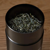 Open tin of All The Rare Leaves luxury single origin tea gift set by August Uncommon Tea, showcasing vibrant, premium loose leaf tea leaves.