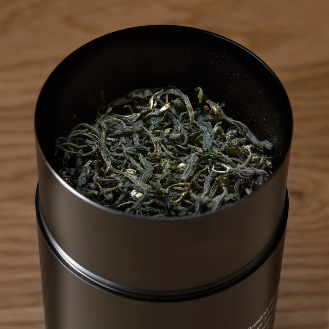 Single estate Pi Lo Chun green tea from Rare Leaves Emerald by August Uncommon Tea, fresh green tea leaves in a transparent container.