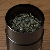 Single estate Pi Lo Chun green tea from Rare Leaves Emerald by August Uncommon Tea, fresh green tea leaves in a transparent container.