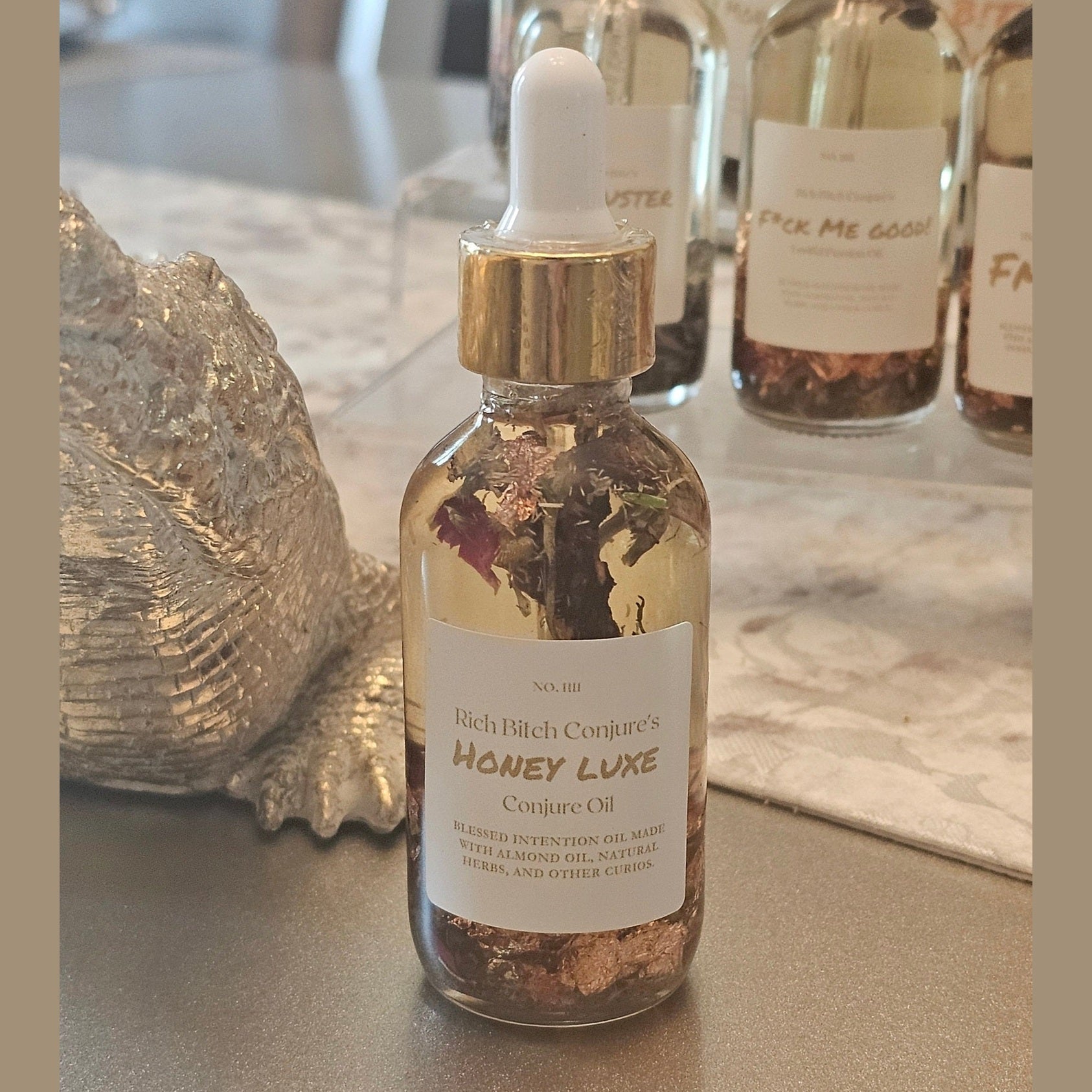 Rich Bitch Conjure Honey Luxe Hoodoo Oil for love and prosperity, featuring a luxurious golden oil in a glass bottle.