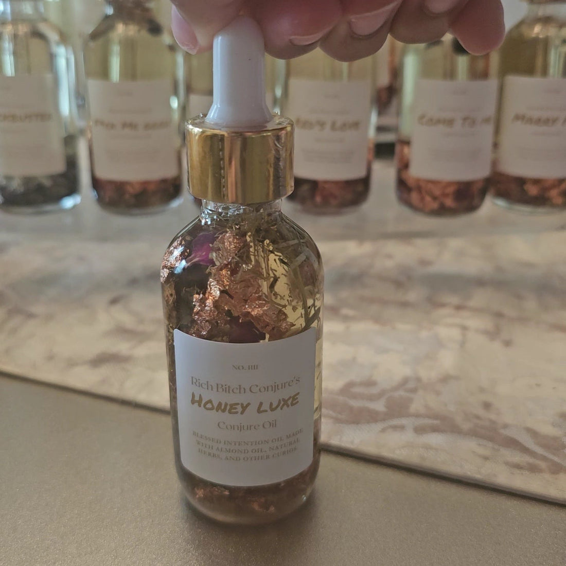 Rich Bitch Conjure Honey Luxe Conjure Oil, a luxurious hoodoo oil blend for love and prosperity, shown in a dark glass bottle.