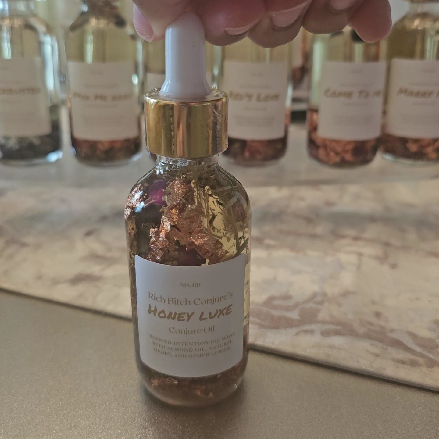 Rich Bitch Conjure Honey Luxe Conjure Oil, a luxurious hoodoo oil blend for love and prosperity, shown in a dark glass bottle.