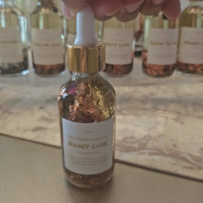 Rich Bitch Conjure Honey Luxe Conjure Oil, a luxurious hoodoo oil blend for love and prosperity, shown in a dark glass bottle.