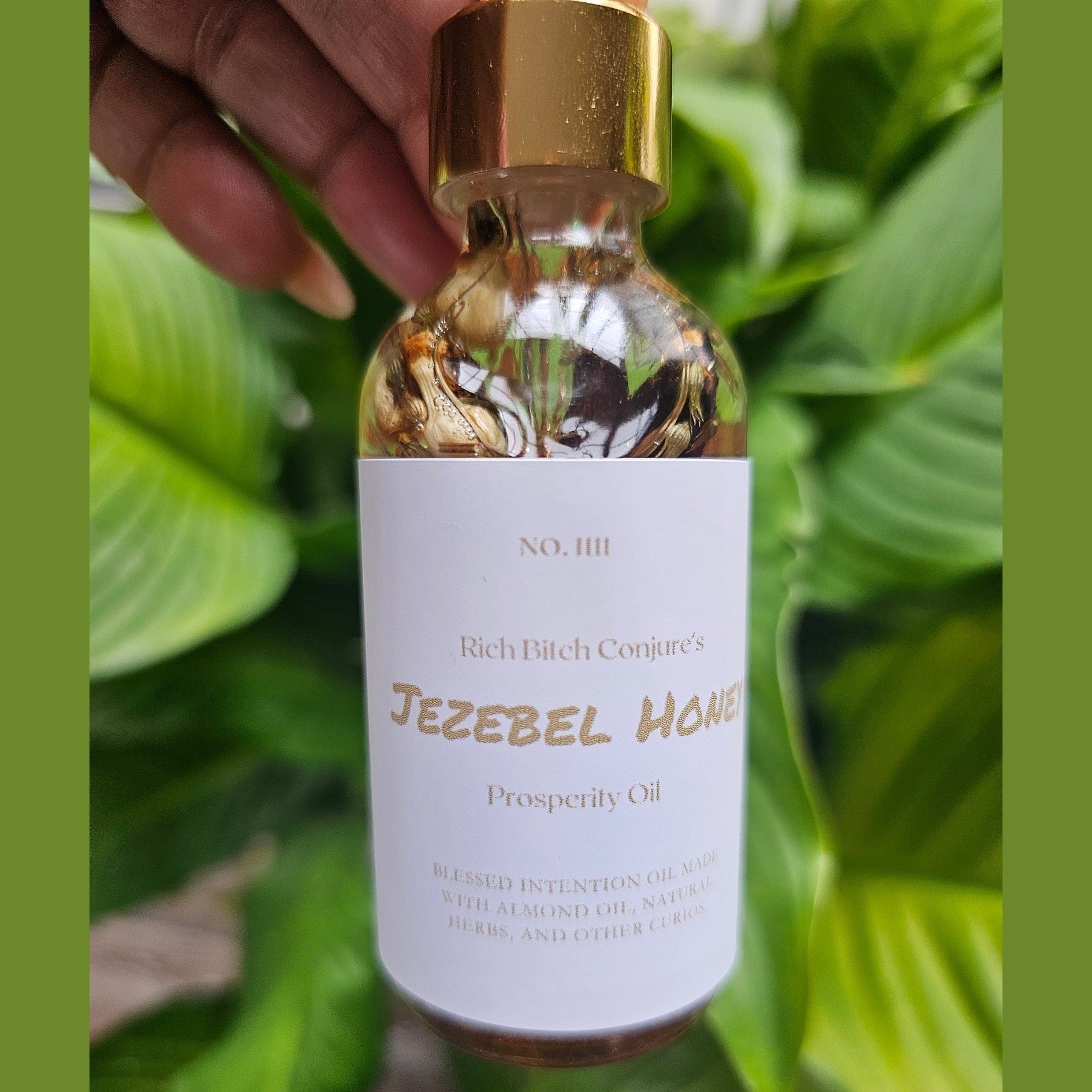 Rich Bitch Conjure Jezebel Honey Oil hoodoo oil bottle with a golden label and black cap, displayed on a wooden surface.