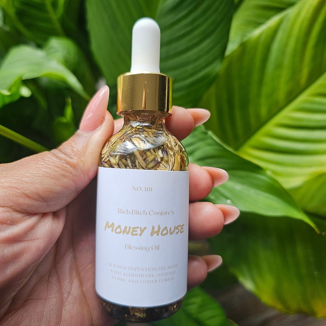 Rich Bitch Conjure Money House Blessing Oil in a small glass bottle with a dropper, used for hoodoo rituals.