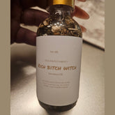 Rich Bitch Conjure Hoodoo Oil bottle labeled "Rich Witch Bitch" with dark liquid inside and decorative label.