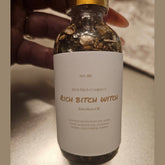 Rich Bitch Conjure Hoodoo oil bottle labeled "Rich Witch Bitch" on a dark background, showcasing the intuitive oil for spiritual practice.