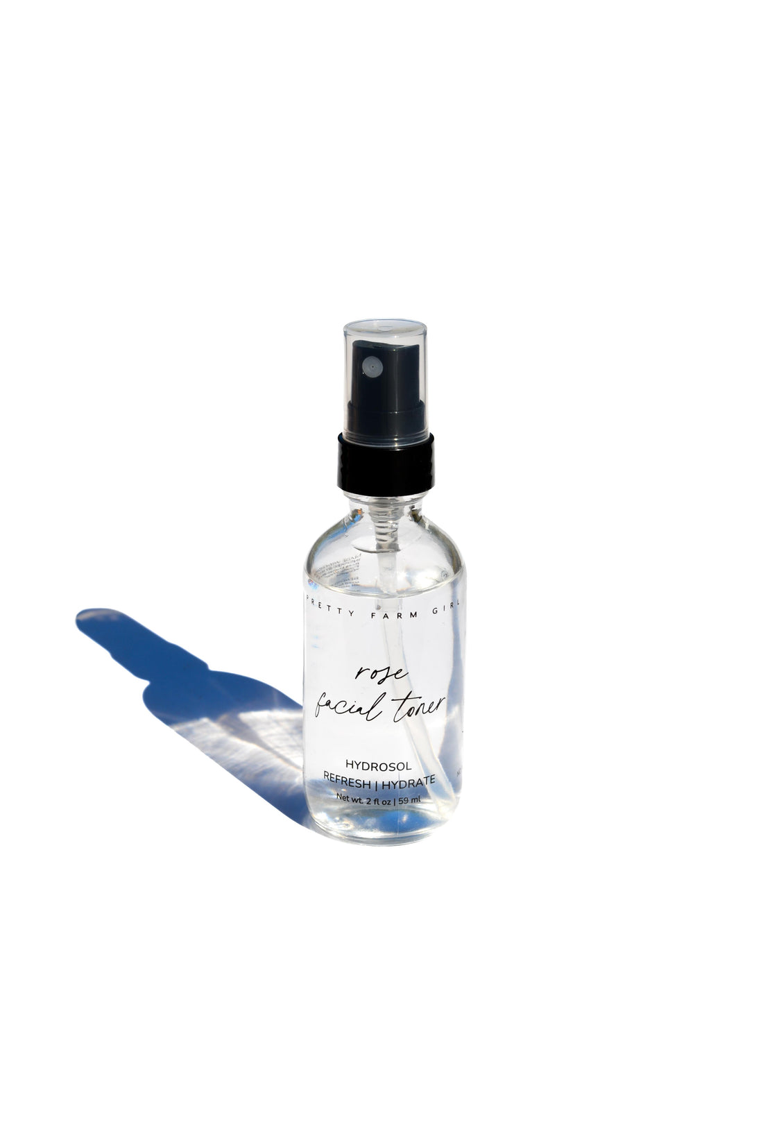 Organic Pure Rose Facial Toner by Pretty Farm Girl in a 2oz bottle, featuring a clear liquid with rose petals visible inside.