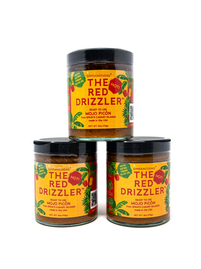 Red Mojo Picón bottle labeled The Red Drizzler Hot from Simrancooks, featuring vibrant red sauce in a clear glass jar.