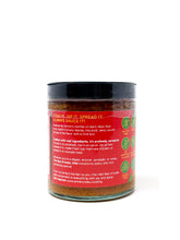 The Red Drizzler Mojo Rojo mild sauce in a clear glass jar with a red label, featuring a spoon drizzling the vibrant red sauce.