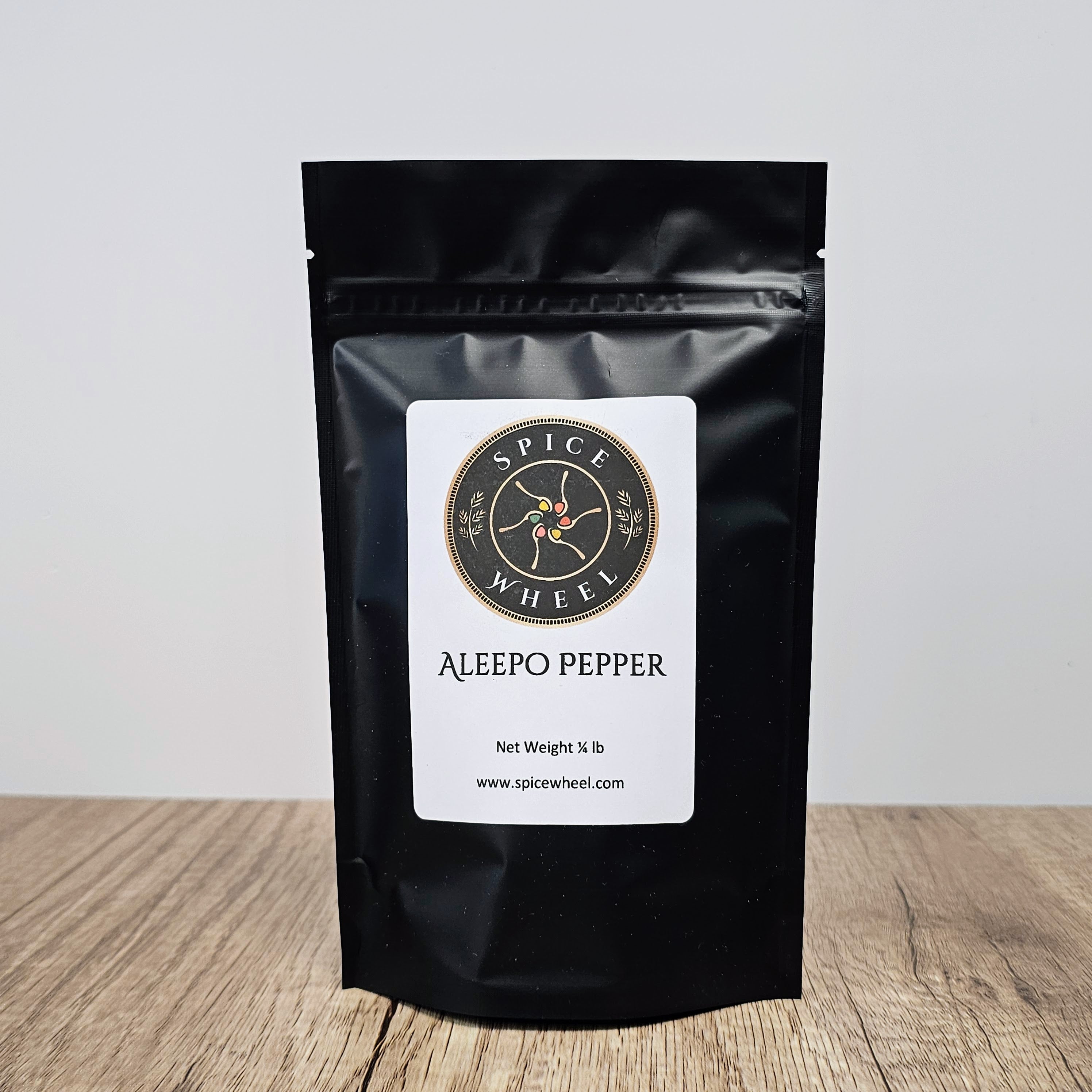 A 1/4 lb package of Aleepo Pepper from Spice Wheel, a vibrant bulk spice with red and green peppercorns in a clear container.