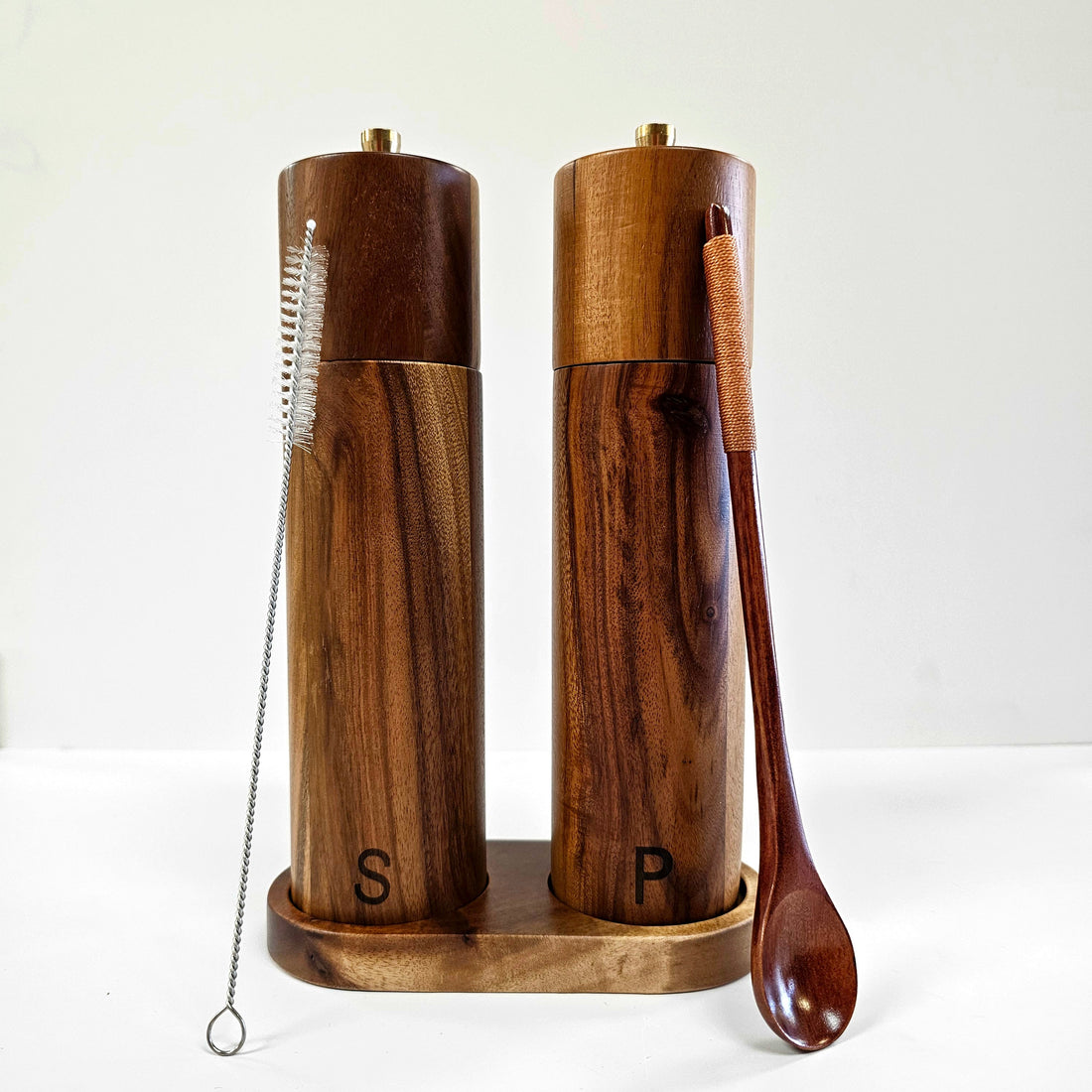 Acacia wood salt and pepper grinders in containers by Spice Wheel, showing the elegant wooden design and grinding mechanisms.