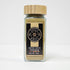 Fine greenish-brown anise seed powder in a clear glass jar from Spice Wheel, showing its smooth texture and aromatic quality.