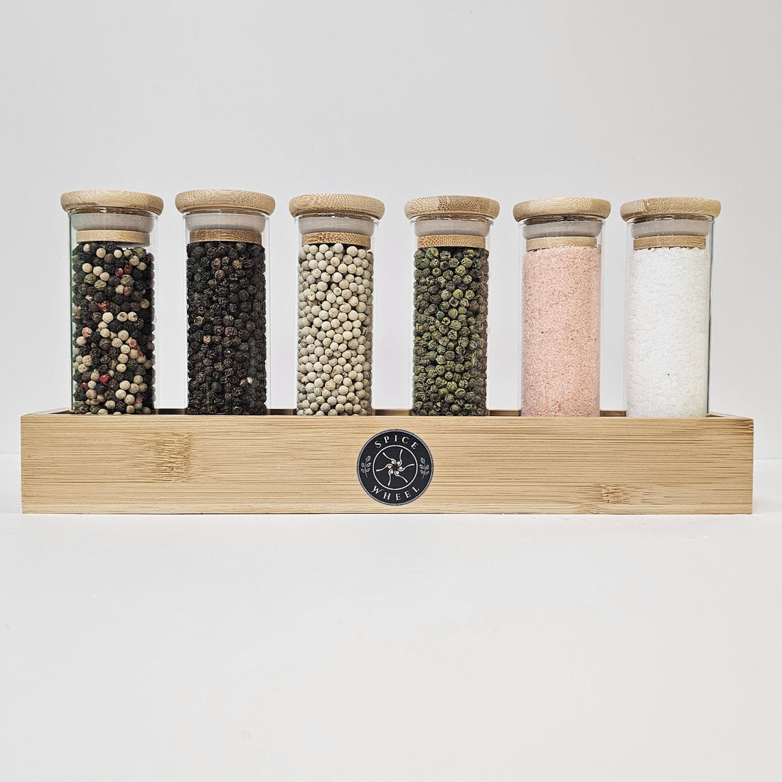 Salt and pepper collection from Spice Wheel, featuring stylish ceramic shakers with metallic accents on a wooden surface.