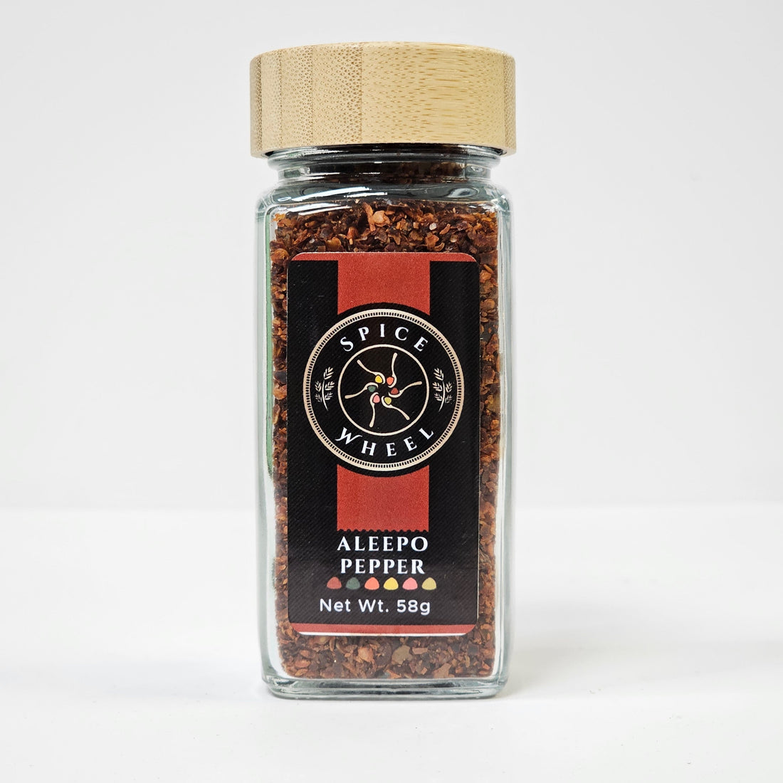 Glass jar of Aleepo Pepper from Spice Wheel, filled with vibrant, whole red peppers in a clear container on a white background.