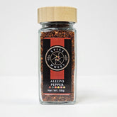 Glass jar of Aleepo Pepper from Spice Wheel, filled with vibrant, whole red peppers in a clear container on a white background.
