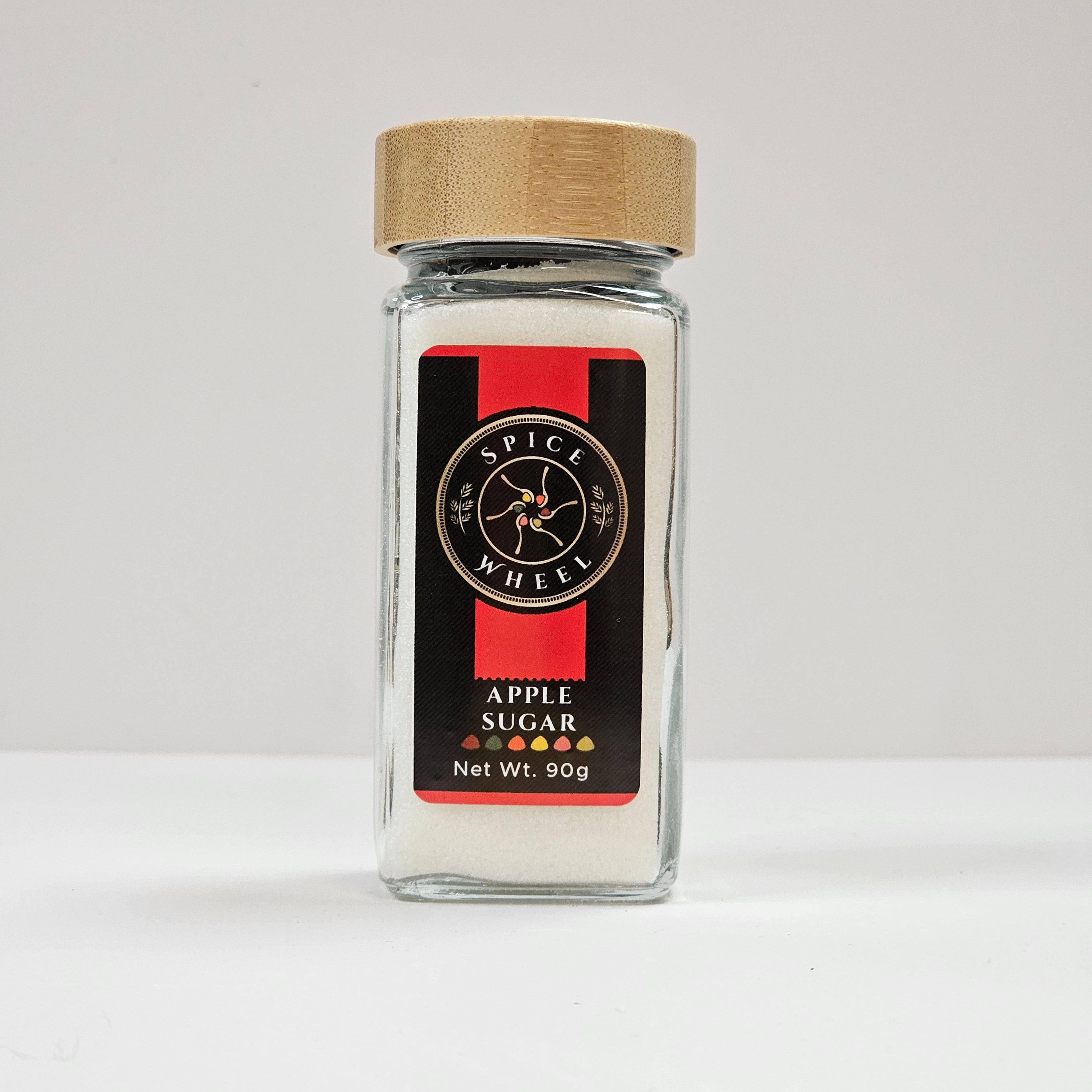 Glass jar of apple sugar from Spice Wheel with a clear label and a metal lid, containing sweet apple-flavored sugar in a compact container.