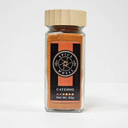 Glass jar of cayenne pepper by Spice Wheel, showing vibrant red cayenne peppers inside the clear glass container.