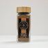 Ground nutmeg in a glass jar by Spice Wheel, showing finely ground spice with a textured surface inside the clear container.