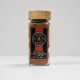Glass jar of Spice Wheel Guajillo Powder with red chili powder inside, labeled container on a white background.