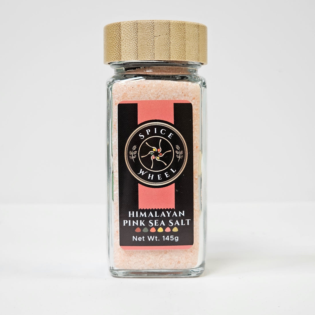 Himalayan pink sea salt in a clear glass jar, showcasing the coarse pink crystals, from Spice Wheel.