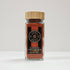 Glass jar of Spice Wheel Kashmiri chili powder with vibrant red chili flakes inside.