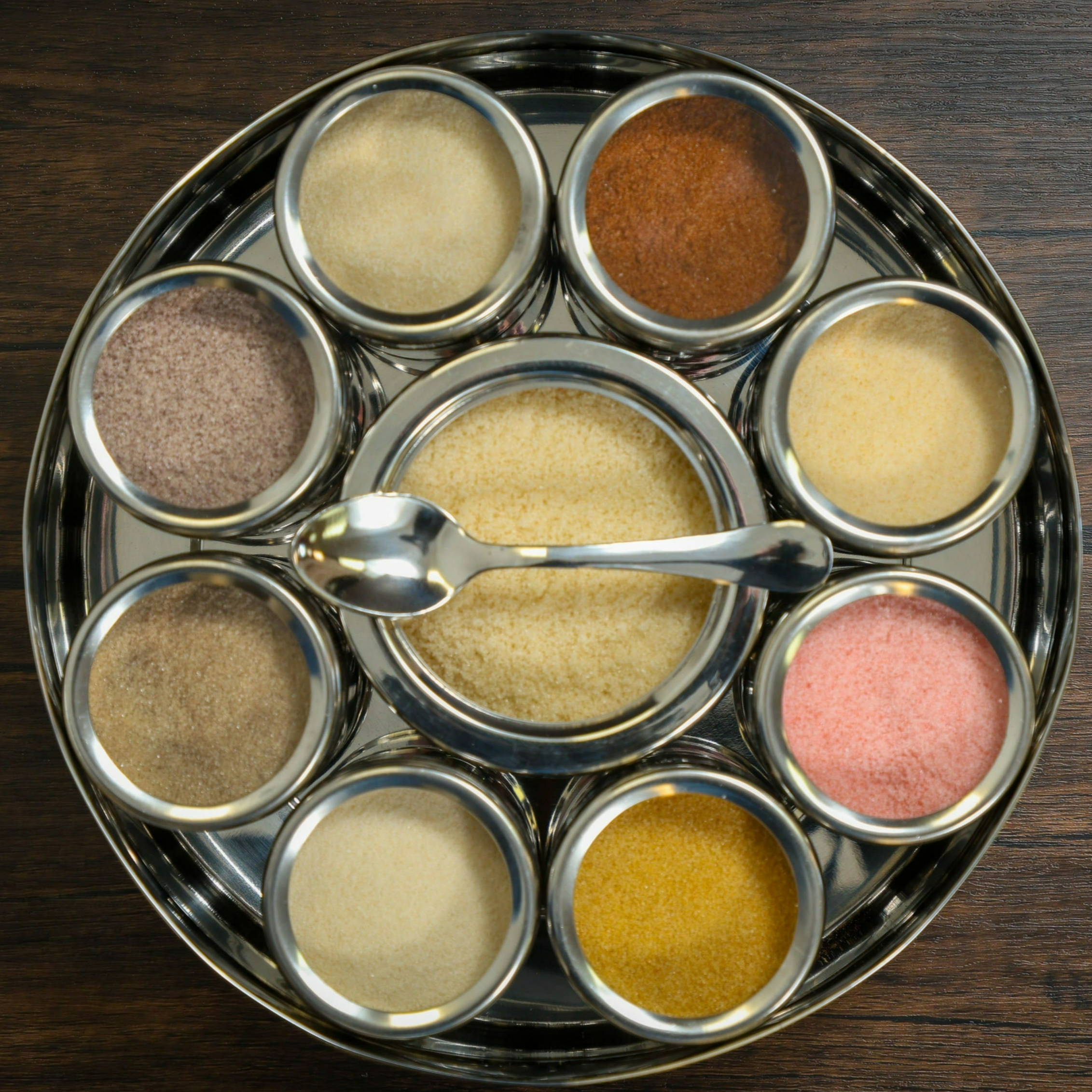 Colorful Spice Wheel with flavored sugar spices on a wooden surface, showcasing various spice segments for baking and cooking.