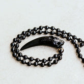 Dark obsidian wolf pendant necklace from Conscious Items featuring a detailed wolf design on a black cord.