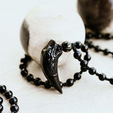 Black obsidian wolf pendant necklace from Conscious Items featuring a detailed wolf design on a sleek cord.
