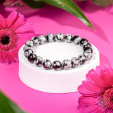 Snowflake Obsidian bracelet from Conscious Items featuring polished black stones with white snowflake patterns, designed for stylish wear.