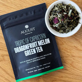 Four cups of Tropic of Capricorn Dragonfruit Melon Green Tea by August Uncommon Tea on a wooden table.