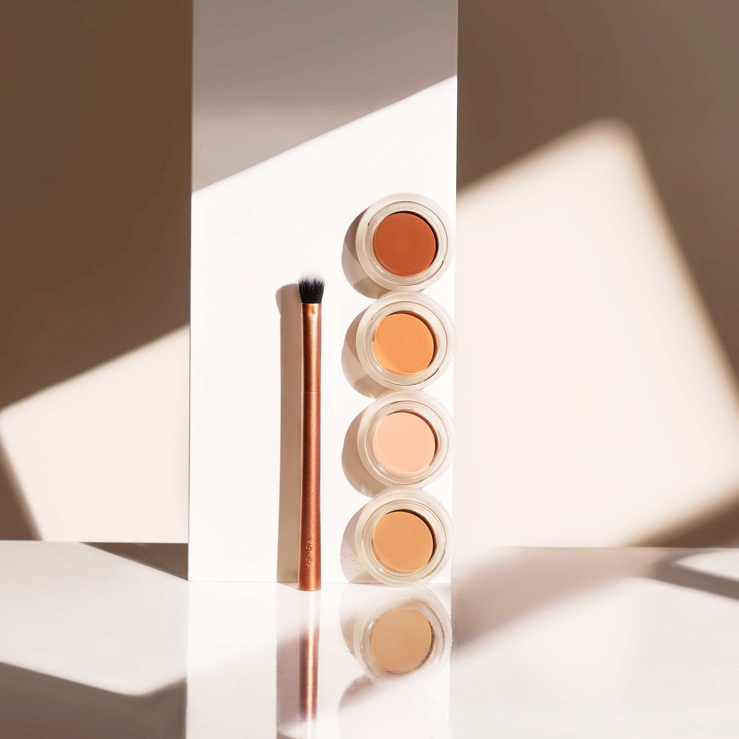 YENSA Super Bright Dark Circle Serum Peptide Corrector eye concealer in various shades, showing smooth, creamy texture on skin.